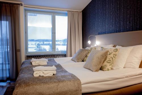1 dormitorio con 1 cama grande y toallas. en Ikaalinen SPA & Resort, en Ikaalinen