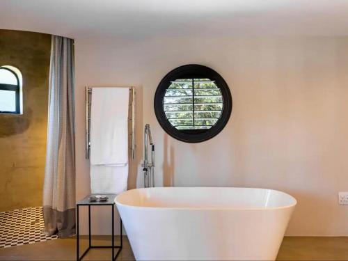 a white tub in a bathroom with a window at Devon Castle Forest Lodge in Stellenbosch