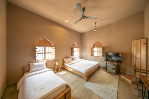 a bedroom with two beds and a flat screen tv at Alaqur View Inn نزل واجهة العقر in Nizwa