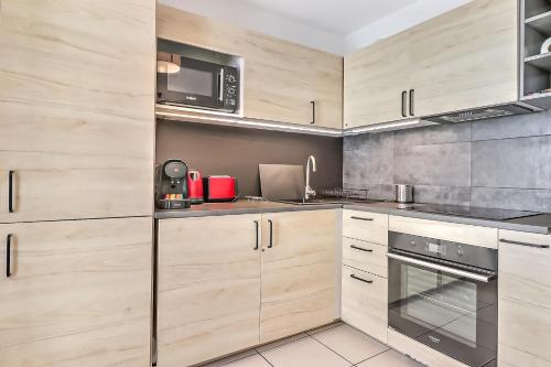 - une cuisine avec des placards en bois et un four micro-ondes dans l'établissement L'Ecluse - Clim - Parking - Central, à Nîmes