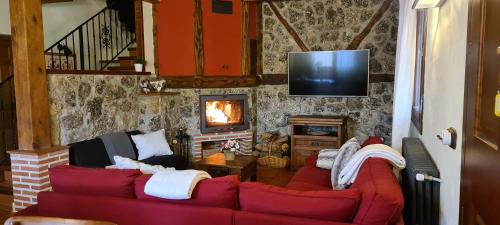 sala de estar con 2 sofás rojos y TV en Casas Rurales Hoces del Duratón, en Carrascal del Río