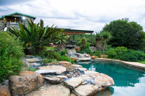 a swimming pool with rocks in a yard at Spion Kop Lodge in Winterton