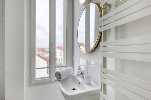 een badkamer met een wastafel, een spiegel en een raam bij STUDIO Escale, 15 min de PARIS, à 200m du RER A in Sartrouville