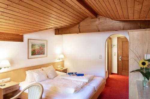 a bedroom with a large white bed with a wooden ceiling at Hotel Zimba in Schruns