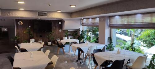 a restaurant with white tables and chairs and windows at Poseidonio in Piraeus