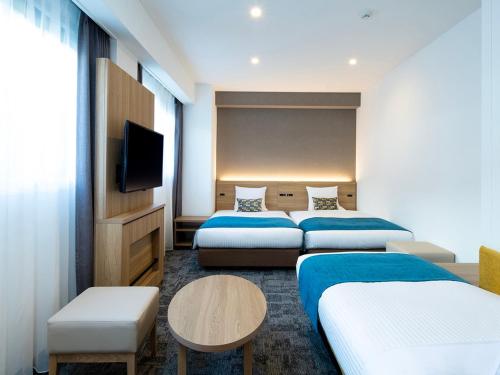 a hotel room with two beds and a flat screen tv at FLEXSTAY INN Shinurayasu in Urayasu