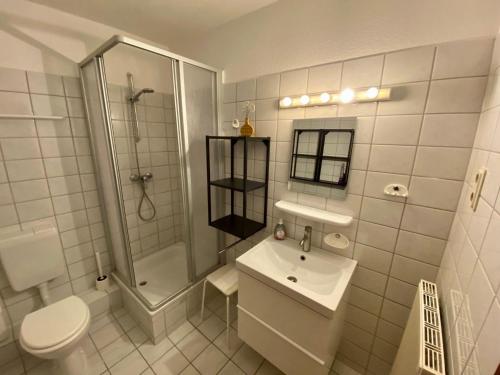 a white bathroom with a toilet sink and a shower at Ferienwohnung-Peter-Pan-mit-Sonnenterrasse-Garten-zwischen-Strand-Wald-Wiese-auf-Ruegen in Gustow