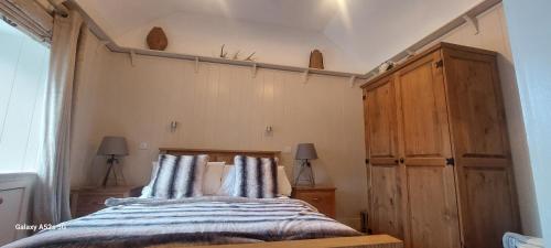 a bedroom with a bed and a wooden cabinet at Fairdene Cottage in Ballater