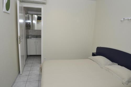 a bedroom with a white bed and a kitchen at Hôtel Des Arceaux in Saint-Sever