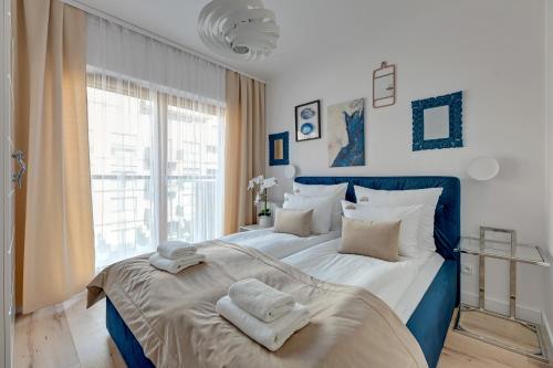 a blue and white bed in a room with a window at Downtown Apartments Riverside Nadmotławie - Gym & Free Parking in Gdańsk