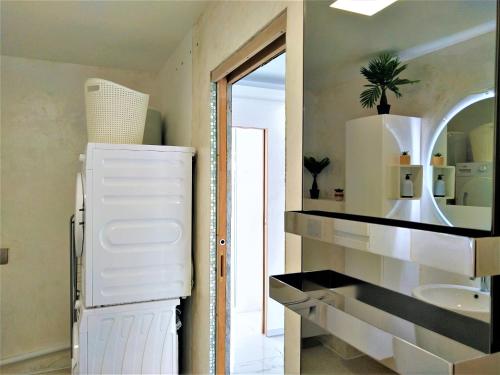 La cuisine est équipée d'un réfrigérateur blanc et d'un évier. dans l'établissement Magnifique maison moderne et atypique au mobilier italien - quartier Sapiac - Piscine et parking privés gratuits - Climatisation, à Montauban