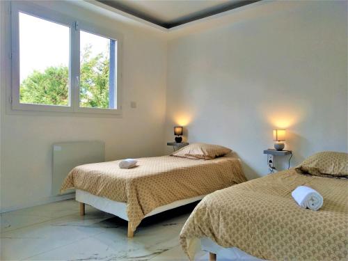 um quarto com 2 camas e uma janela em Magnifique maison moderne et atypique au mobilier italien - quartier Sapiac - Piscine et parking privés gratuits - Climatisation em Montauban