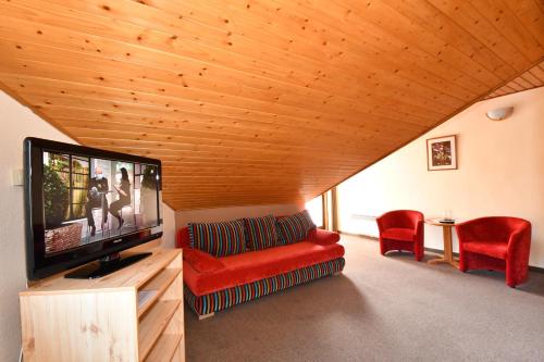 a living room with a red couch and a flat screen tv at Penzión Lesnica in Spišské Tomášovce