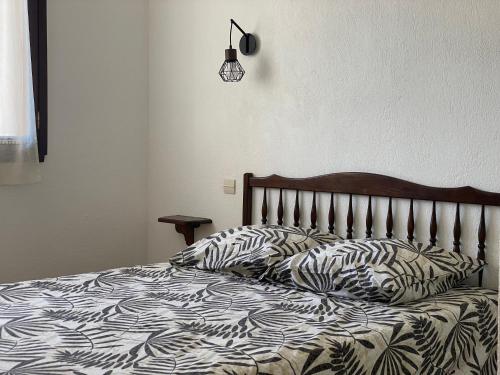 ein Bett mit einer schwarzen und weißen Bettdecke und Kissen in der Unterkunft Motel Esterel in Mandelieu-la-Napoule