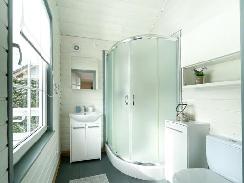 a bathroom with a shower and a toilet and a sink at By The Sea Lodges in Wrzosowo