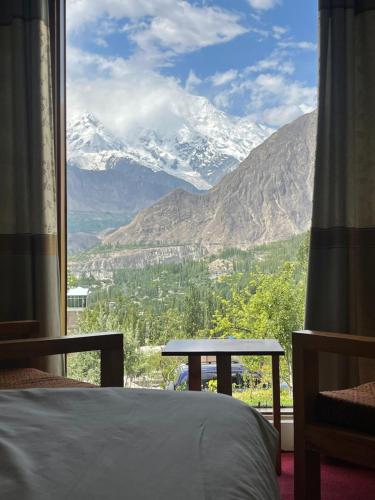 a bedroom with a view of a snow covered mountain at applegardenhunza in Alīābād