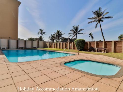 a swimming pool in a yard with palm trees at Holiday Accommodation Amanzimtoti in Amanzimtoti