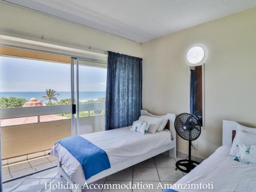 a bedroom with a bed and a balcony with the ocean at Holiday Accommodation Amanzimtoti in Amanzimtoti