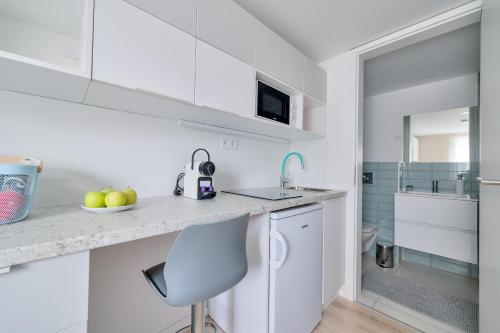 a kitchen with white cabinets and a sink and a chair at Villa Oliver 2 Hévíz in Hévíz