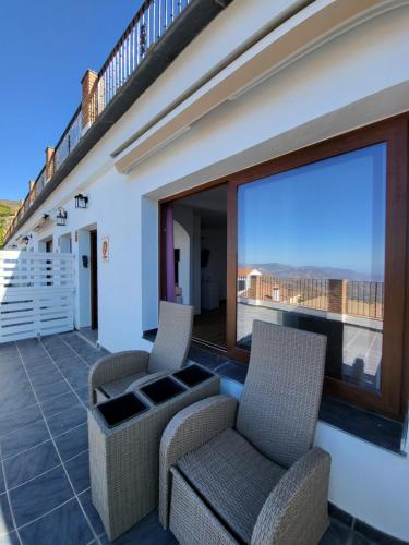 einen Balkon mit 2 Stühlen und einem großen Fenster in der Unterkunft Suite Émber-Fuego in Soportújar