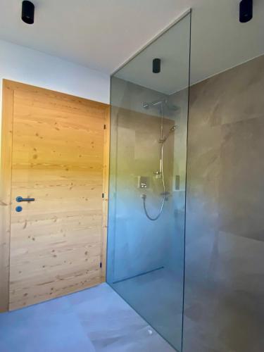 a shower in a bathroom with a wooden wall at Chalet Tuxer in Achenkirch
