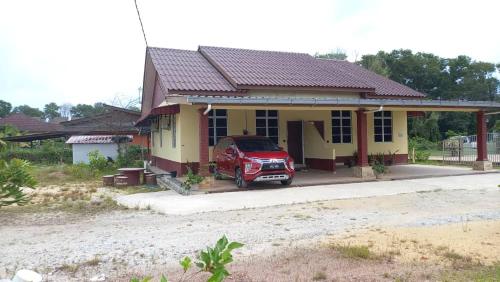 un coche rojo estacionado frente a una casa en Mufeed Homestay, en Kampong Wakaf Tengah