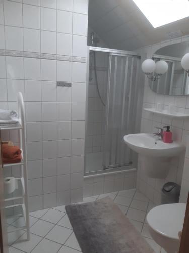 a white bathroom with a shower and a sink at Bed and Breakfast Korswandt 1 in Korswandt