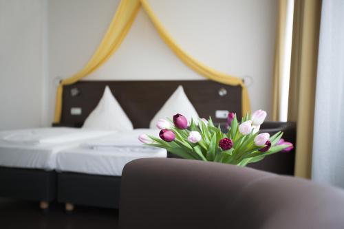 a vase of flowers sitting on a table in a bedroom at Hotel Kiez Pension Berlin in Berlin