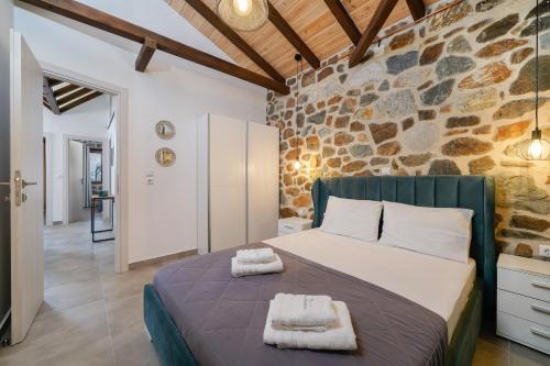 een slaapkamer met een bed en een stenen muur bij Petra Residence in Skala Potamias