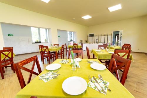 uma sala de jantar com mesas amarelas e cadeiras de madeira em Hotel BIESZCZADski Wańkowa em Wańkowa