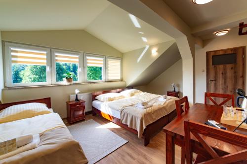 sypialnia z 2 łóżkami i stołem oraz 2 oknami w obiekcie Hotel BIESZCZADski Wańkowa w mieście Wańkowa