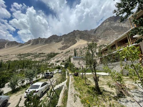 a view of a mountain with cars parked on a road at applegardenhunza in Alīābād
