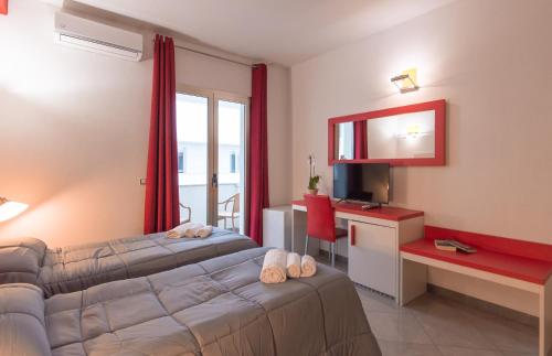 a bedroom with a bed and a desk and a television at Delta Rooms in Olbia