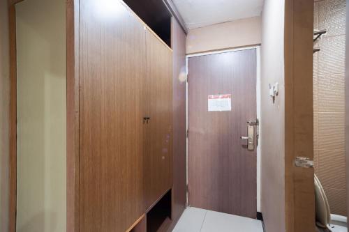 a bathroom with a toilet and a wooden door at Safwah Bintaro Syariah Mitra RedDoorz in Tangerang
