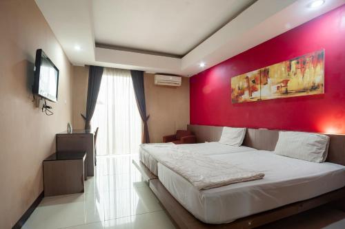 een slaapkamer met een rode accentmuur en een bed bij Safwah Bintaro Syariah Mitra RedDoorz in Tangerang