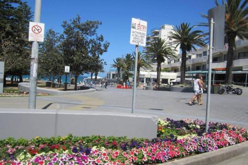 a street with signs and flowers in a park at Eloura Gardens 100m to Beach in Cronulla