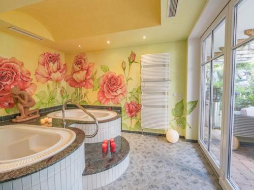 ein Bad mit einer Badewanne und einem Blumenbild in der Unterkunft Wellnesshof Blenk in Wertach