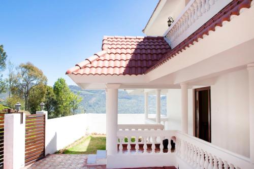 a white house with a balcony with a view at The Royale Ridge in Kotagiri