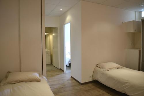 a bedroom with two beds and a hallway at Hôtel Des Arceaux in Saint-Sever