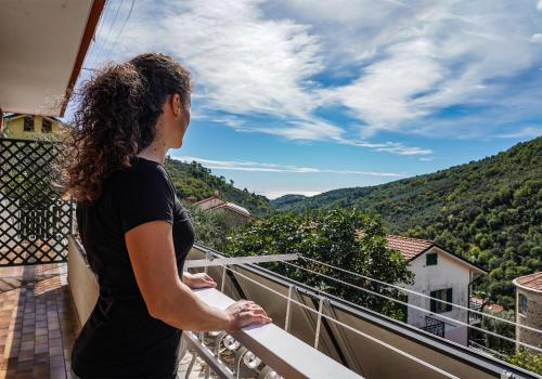 a woman standing on a balcony looking out at the mountains at Agriturismo La Rocca in San Bartolomeo al Mare