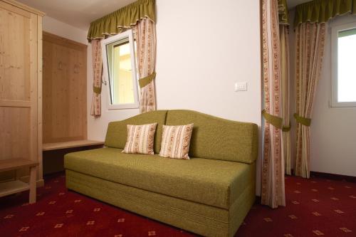 a green couch in a room with a window at Hotel Weiss in Rablà