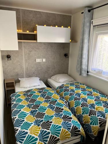 a bedroom with a bed with a colorful quilt at Mobilhome bora bora in Pont-Aven