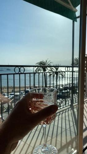 een persoon met een wijnglas voor een balkon bij Primera Línea de Mar y Playa in Roses