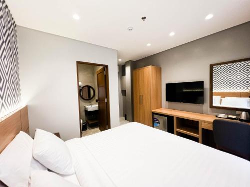 a bedroom with a bed and a desk and a television at The Manaoag Hotel in Manaoag