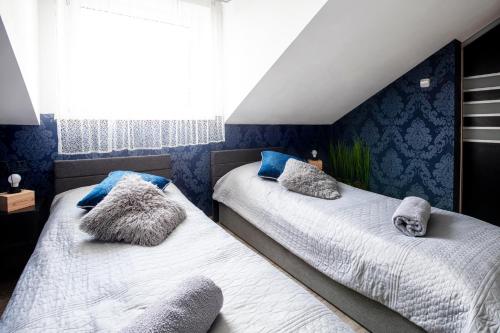 two beds in a bedroom with blue walls at Apartament nad Goplem Bialy in Kruszwica
