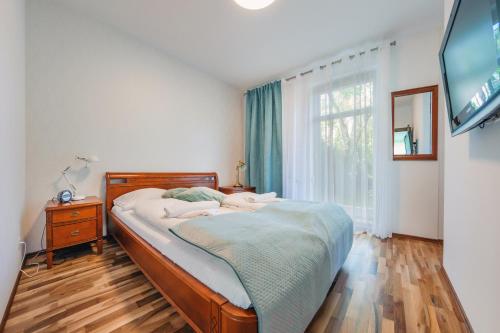 a bedroom with a bed with a television and a window at Apartamenty Sun & Snow Parkur in Sopot