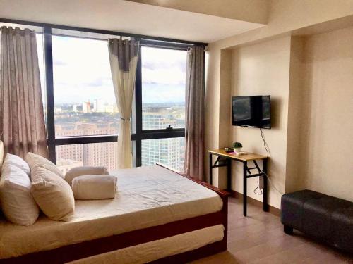 a bedroom with a bed with a large window at AFFORDABLE StayCation EASTWOOD CITY in Manila