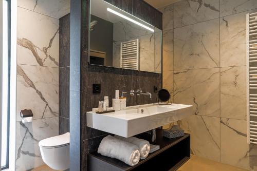 La salle de bains est pourvue d'un lavabo et d'un miroir. dans l'établissement B&B De Scheersehoeve, à Holthone