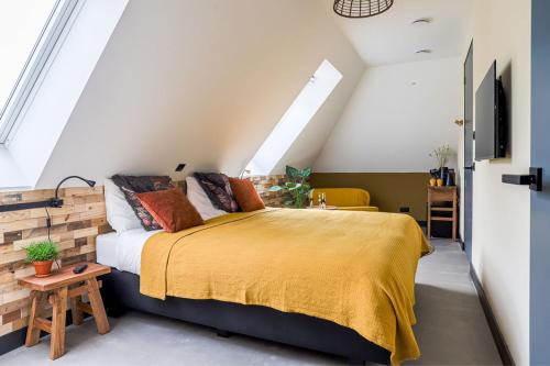 een slaapkamer met een groot bed en een gele deken bij B&B De Scheersehoeve in Holthone