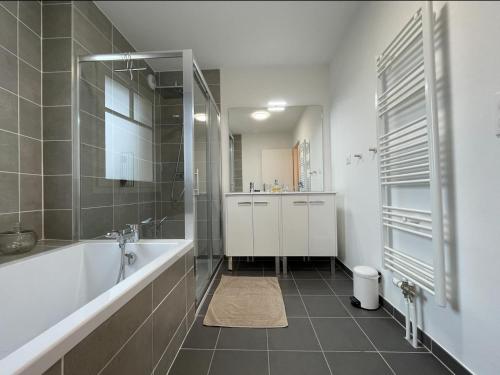 ein weißes Bad mit einer Badewanne und einer Dusche in der Unterkunft La Clé de Quentovic ◎ Duplex de 150 m2 ◎ Standing in Le Touquet-Paris-Plage